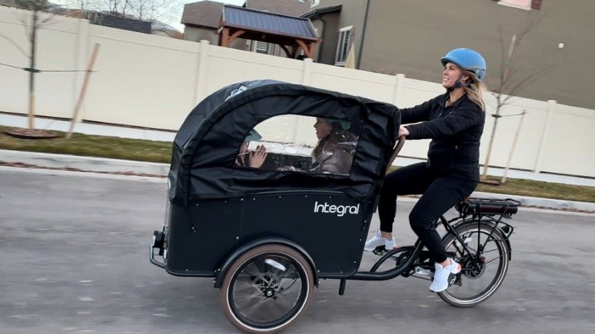 The Integral Electrics Roam front-load cargo e-bike offers spacious storage, adjustable straps, and a comfortable ride, making it ideal for transporting children and goods.